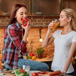 Eat well to be well Young female friends preparing together healthy meal in modern kitchen. Cozy