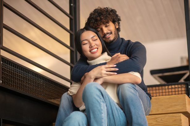 Embraced man with woman sitting on stairs at home