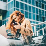 Long haired young woman in glasses opens laptop and working