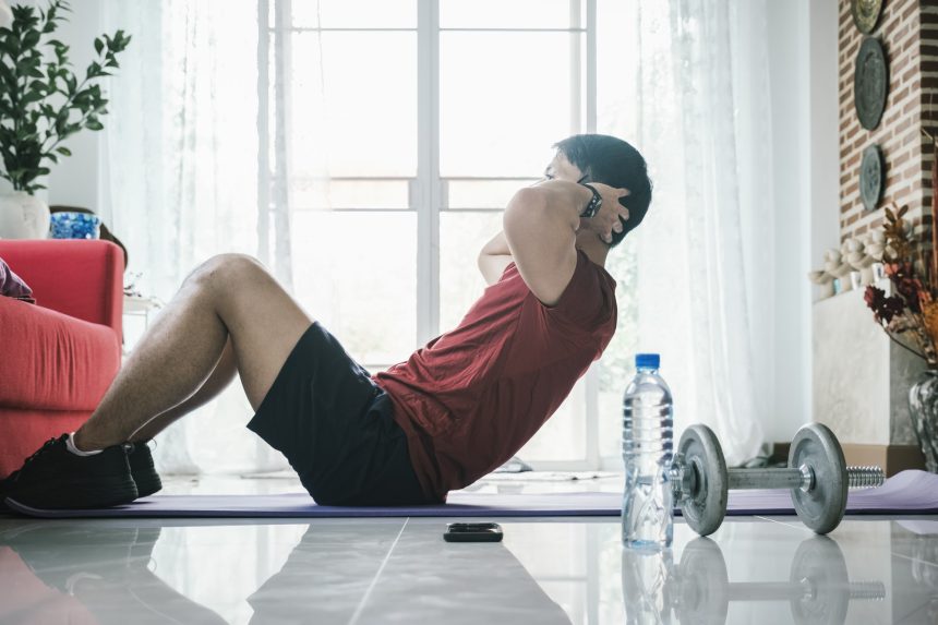 Male fitness instructor showing exercises training at home using laptop.